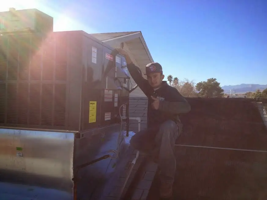 HVAC technician performing HVAC Inspection on a rooftop unit in Lee