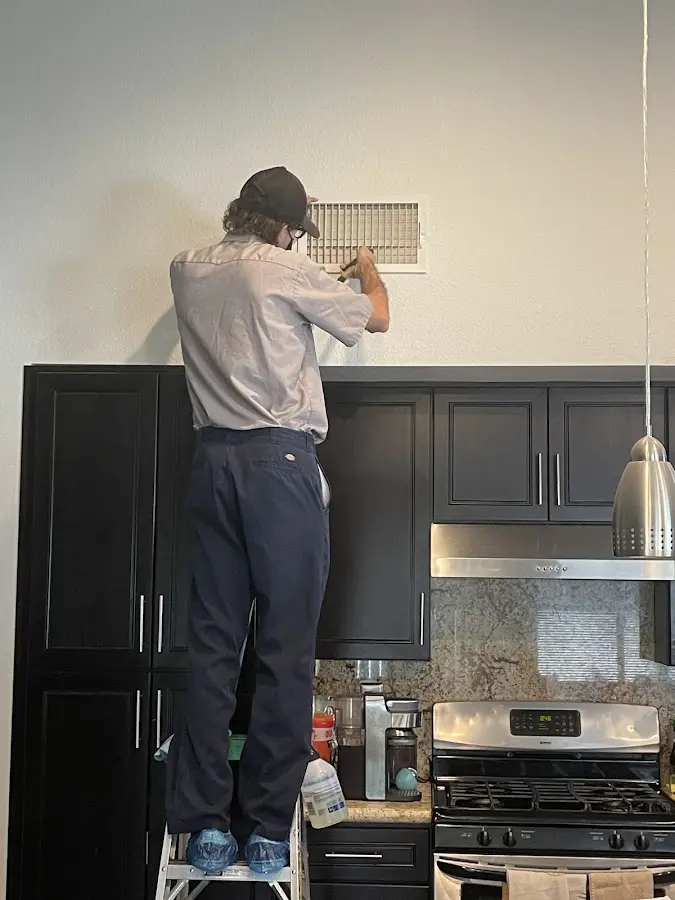 Technician inspecting an air vent during HVAC service in Lee